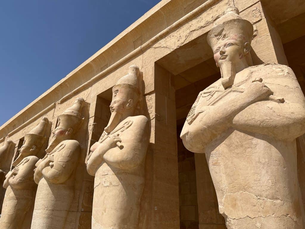 Statues of Queen Hatshepsut outside her temple in Luxor. They are cross armed and wear beards.