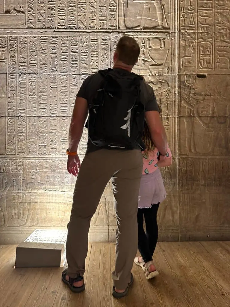 Mr Tin Box and daughter stand looking at a wall of hieroglyphs inside the Temple of Philae