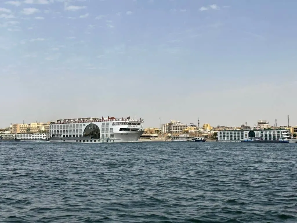 A cruise ship sails down the River Nile at Luxor. It's a windy day and the water is choppy