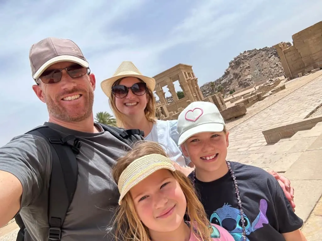 Our family smiling at the camera at the Temple of Philae. You can see columns in the background.