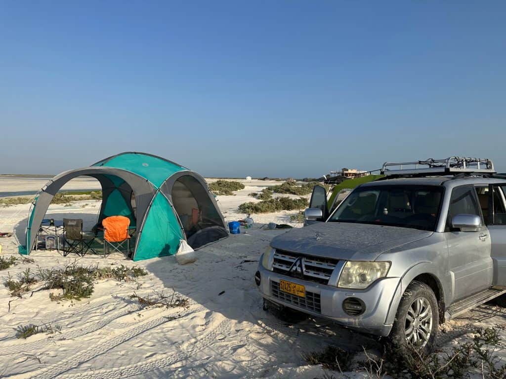 Our car parked on the sand at Barr al Hickman next to our green and grey gazebo