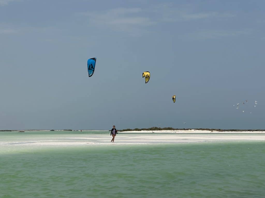 Our eldest daughter waling across a white sand bar at Barr al Hickman with kite surfing kites flying above