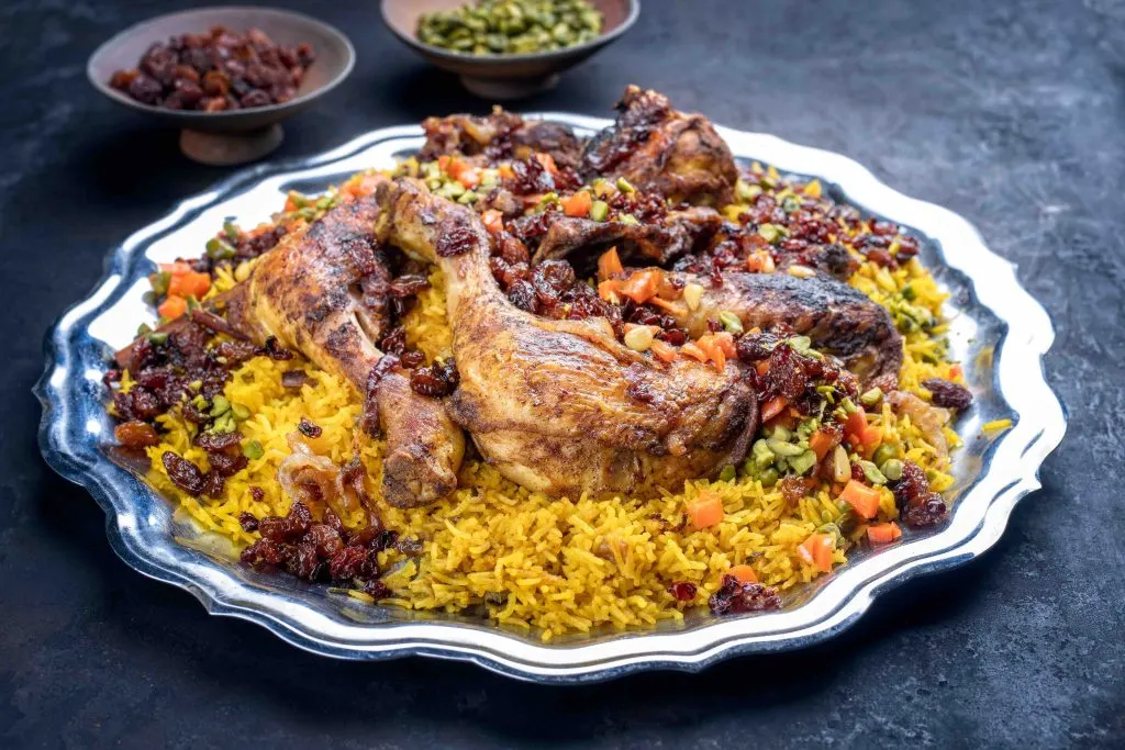 Traditional fried Arabic chicken majboos with chicken leg and jeweled rice served as close-up in a rustic oriental tray
