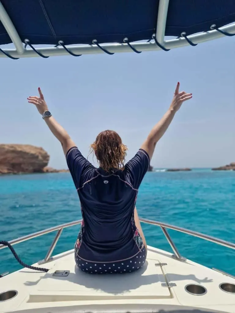 Claire sat at the bow of a boat moored in a turquoise bay in the Daymaniyat Islands