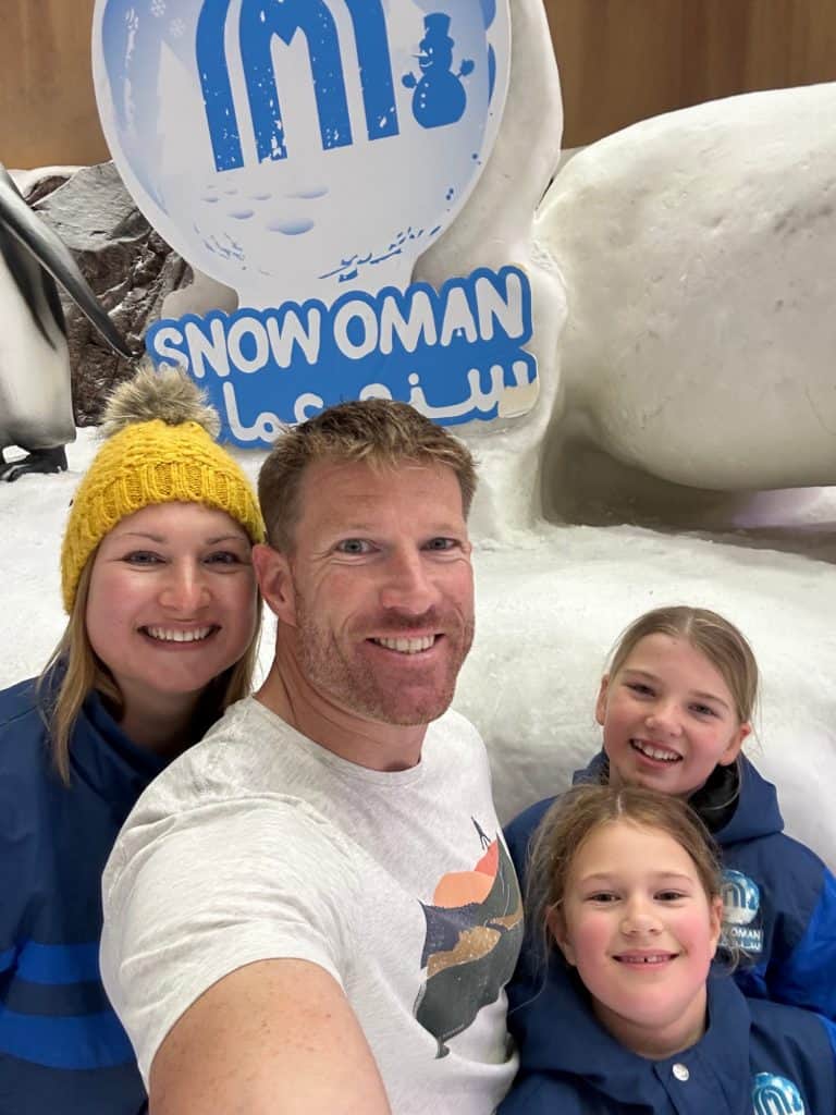 Family smiling in front of Snow Oman sign