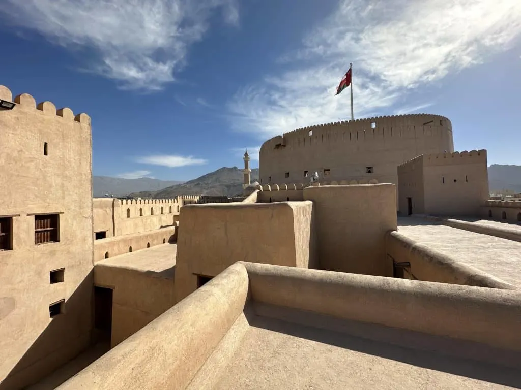 The roof of Nizwa castle with mountains viable beyond the battlements