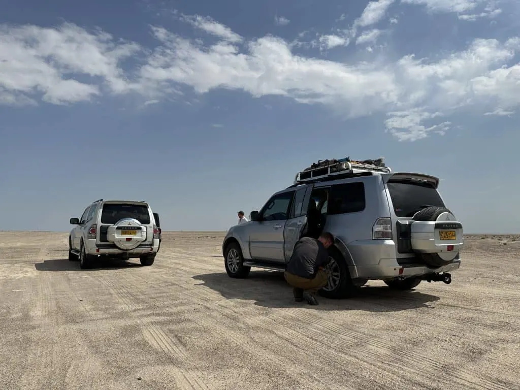 Mr Tin Box letting air out of the rear tyre of our Pajaro 4x4 on the salt flats before Barr al Hickman