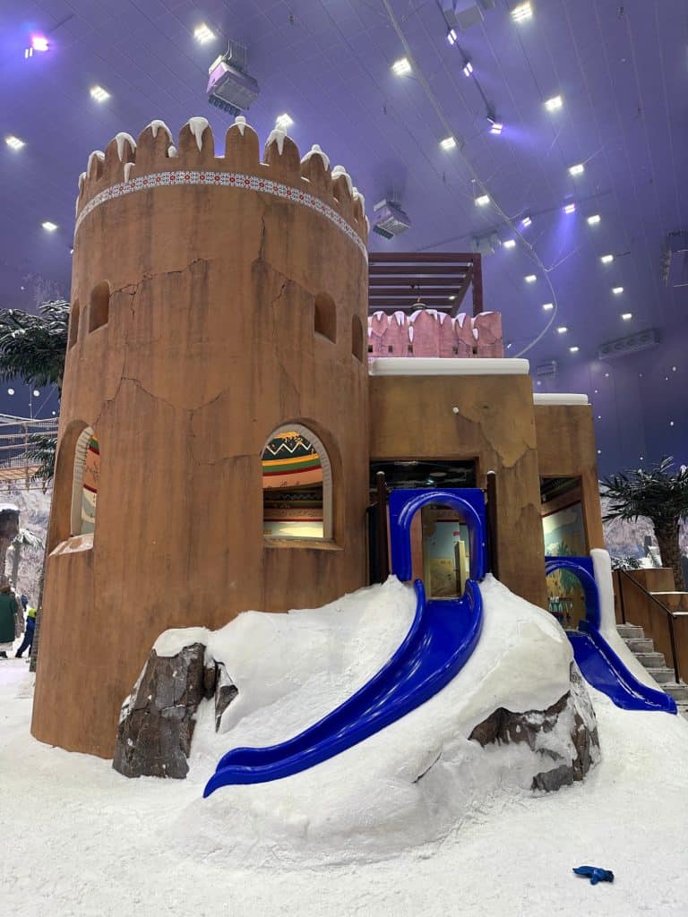 An Omani-style fort with blue children's slides coming out of the doors