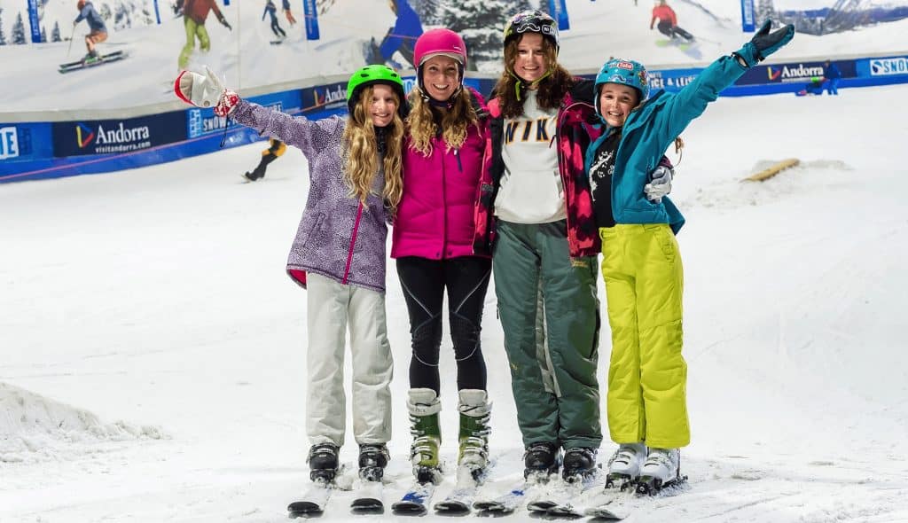 Family posing for photo in ski gear on an indoor ski slope