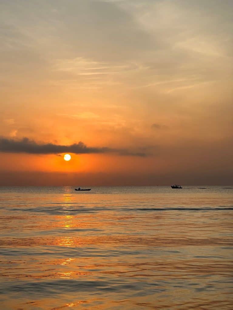 Sun rides over sea in Sri Lanka. Small boats are outlined on the horizon