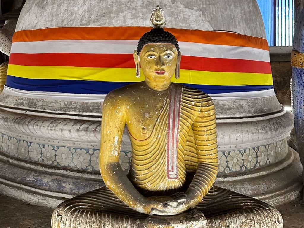 Seated Buddha statue and stupa inside the Dambulla cave temple.