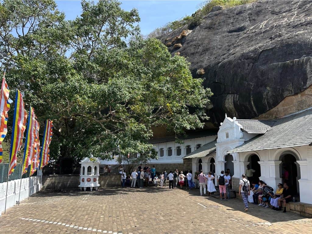 People mingle in the shade in the courtyard outside the Dambulla