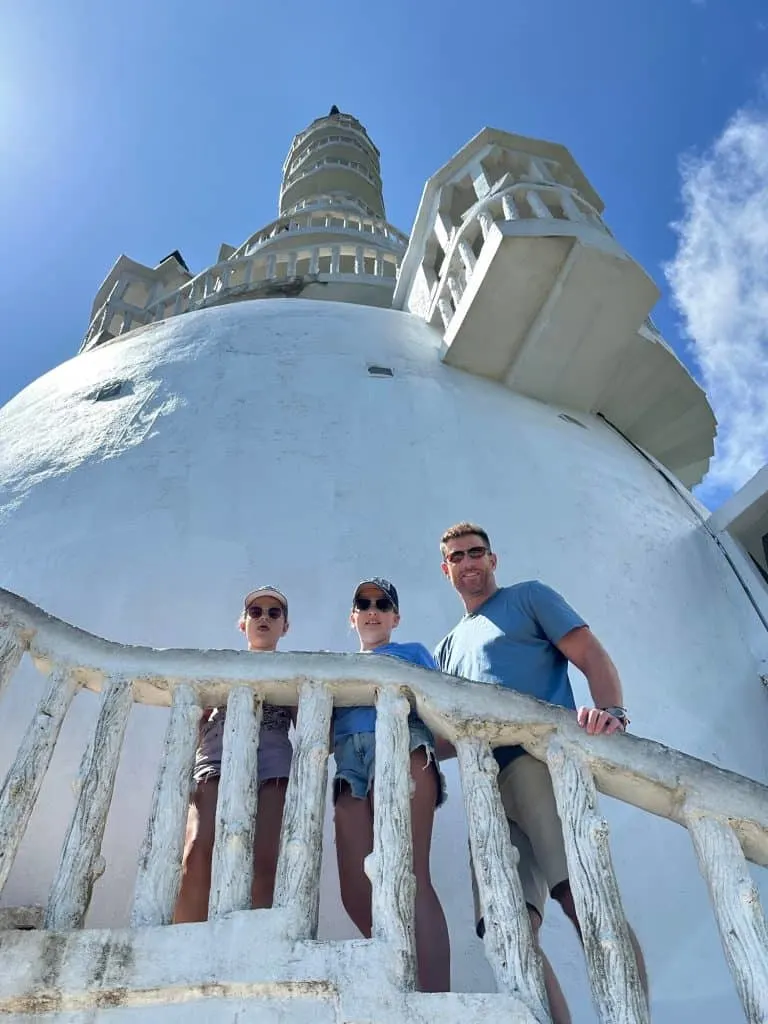 Mr Tin Box and daughters looking down from extra steps of Ambuluwawa Tower with the top of the tower above them