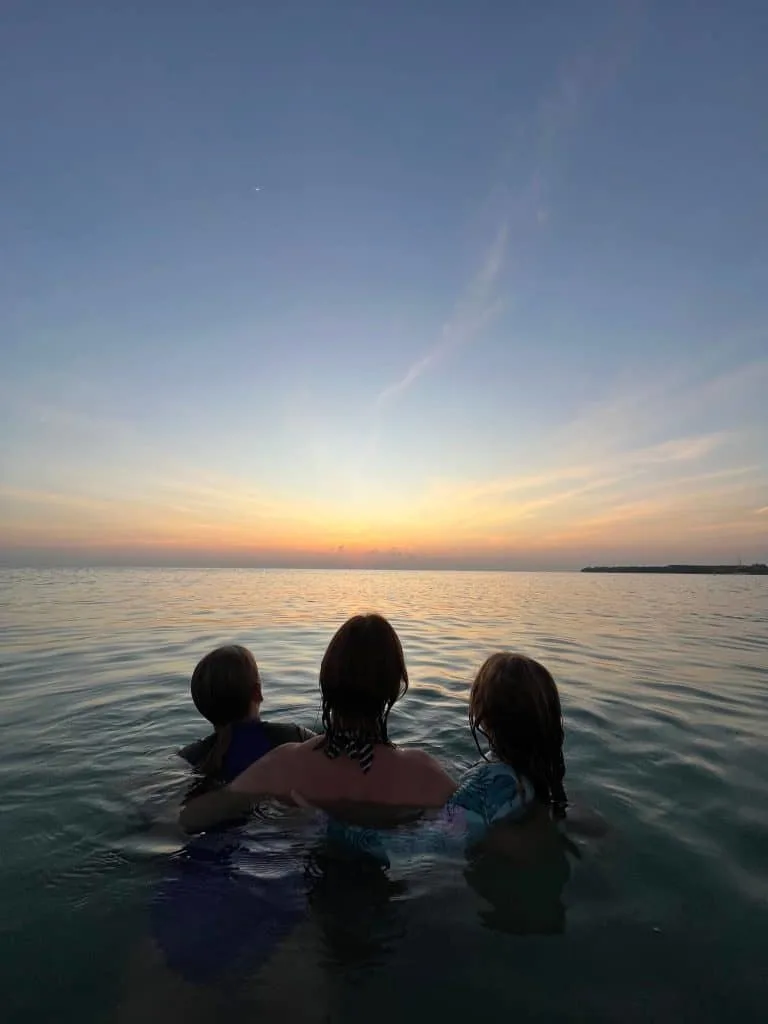 Family in sea looking at sunrise