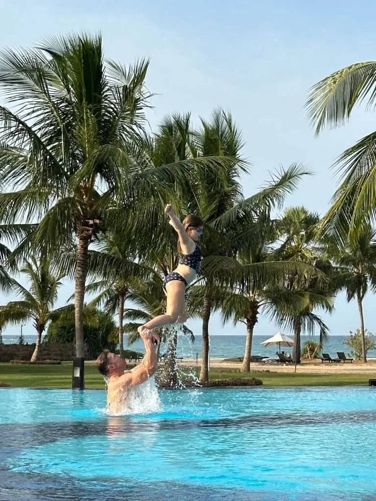 Mr Tin Box lifts daughter up on his hands in the outdoor pool at Cam Resort