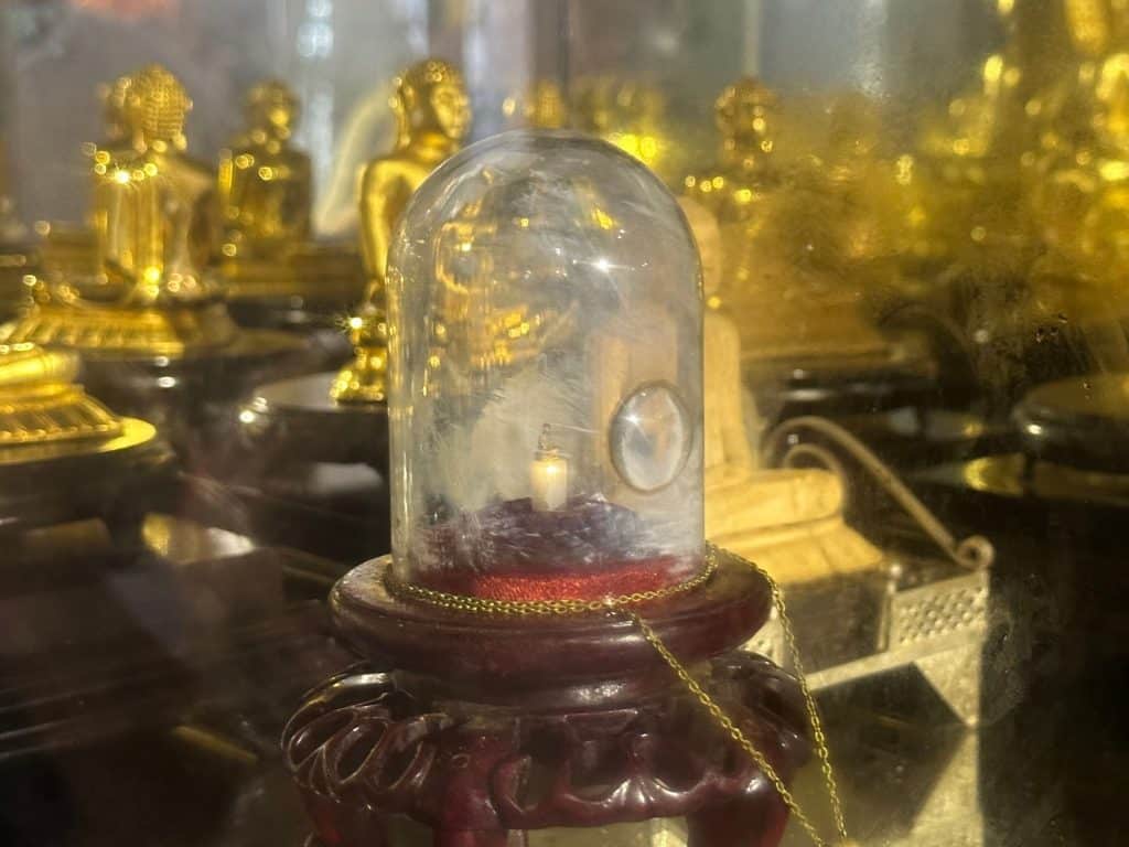 A tiny Buddha statue kept inside a glass dome with a built in magnifying glass