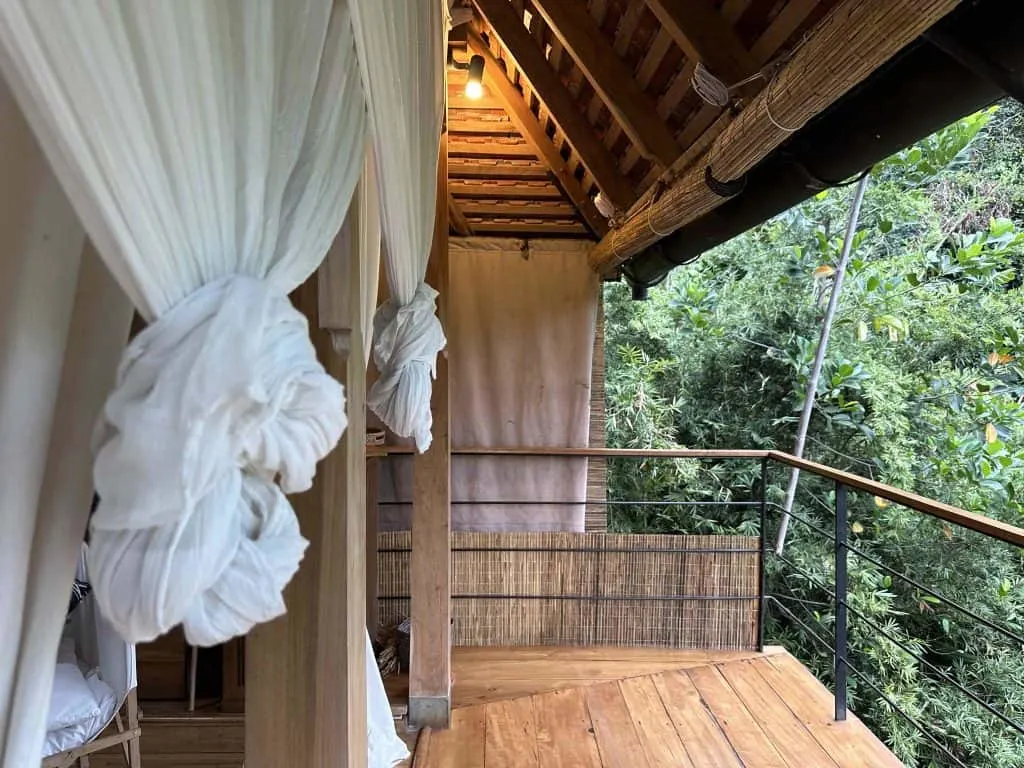 Cheese cloth drapes knotted above forest pavilion balcony