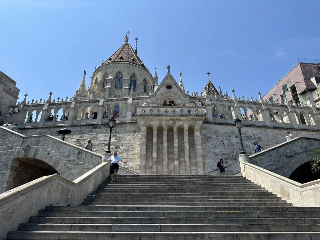 A view looking up towards the Fisherman's Bastion on Castle Hill in Budapest. It is a gothic inspired wall with columns and turrets