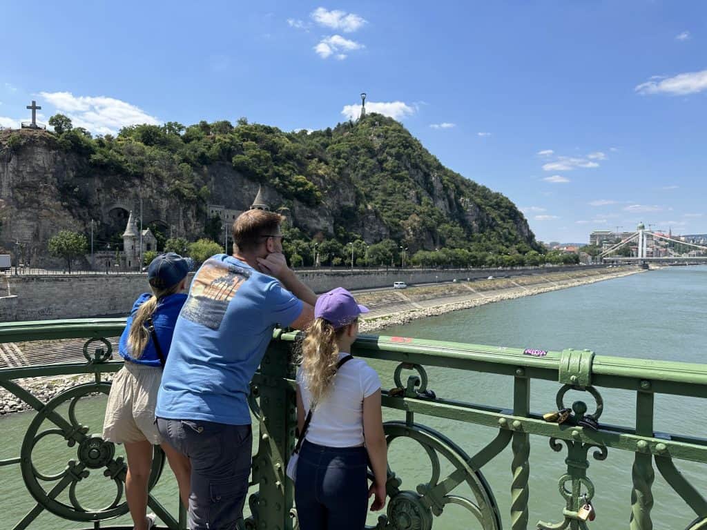 Mr Tin Box and the girls stood on a green bridge looking out at the Danube River in Budapest
