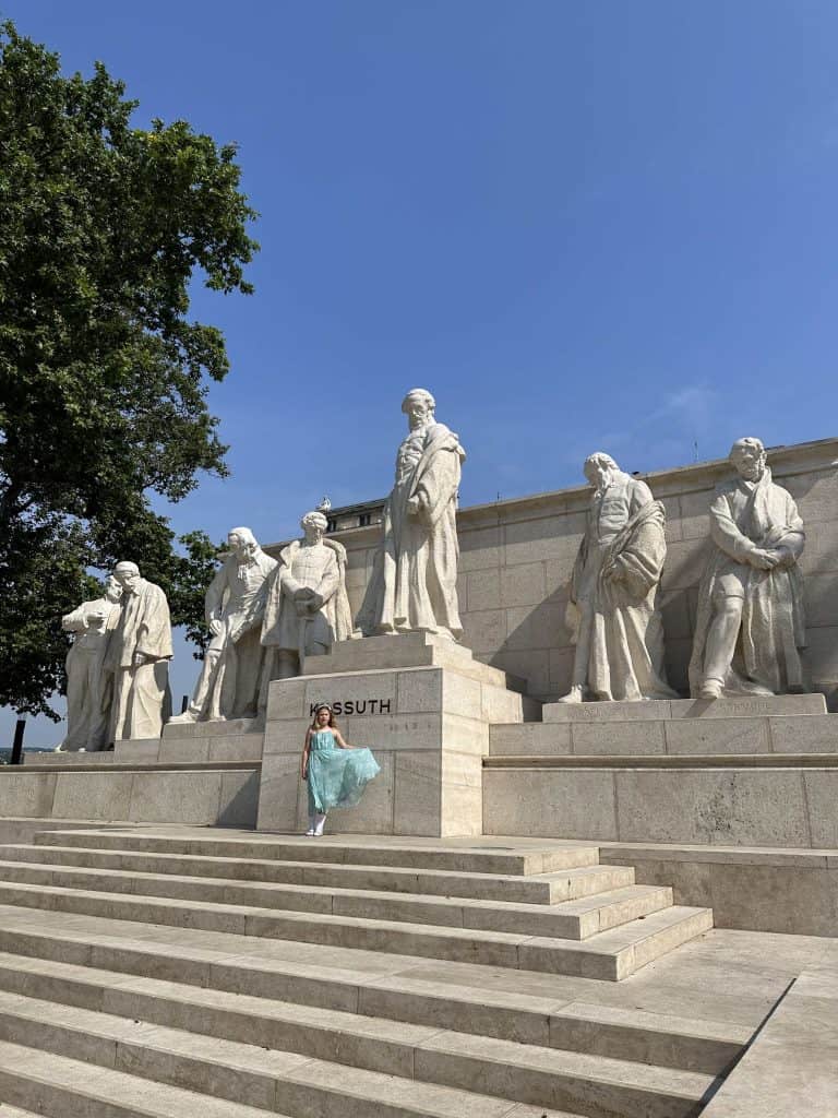 Our eight-year-old stood in front of a row of marble statues near the Hungarian Parliament