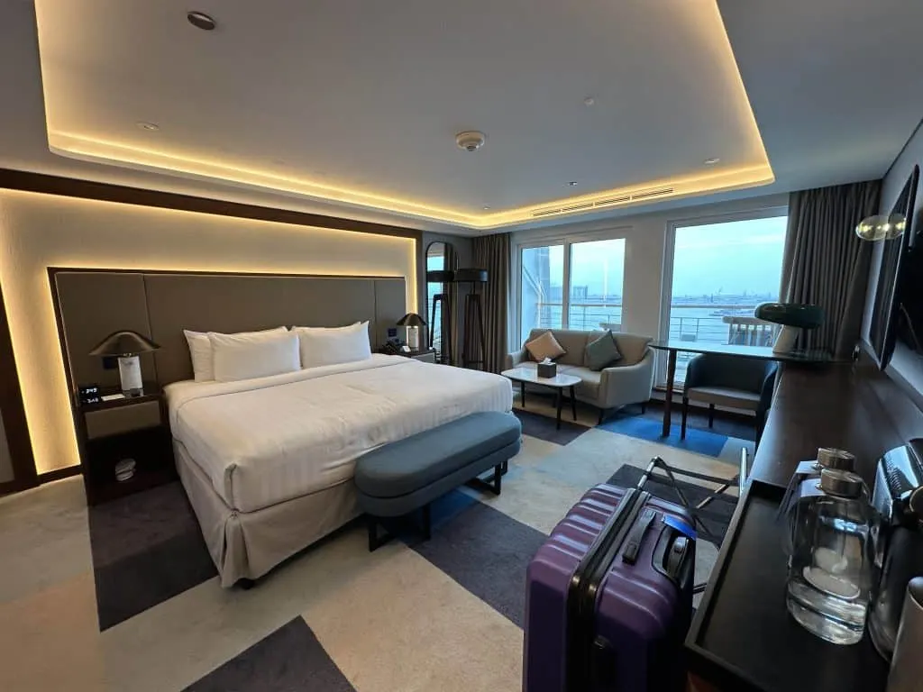 Our Captain's Room with Balcony. there is a king sized bed and seating with two floor to ceiling windows looking out on the port