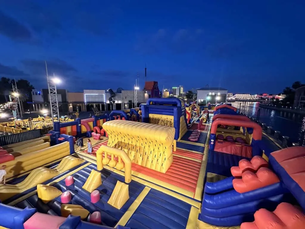 A huge inflatable obstacle course lit up at night. This is there world's largest outdoor inflatable in Riverland in Dubai