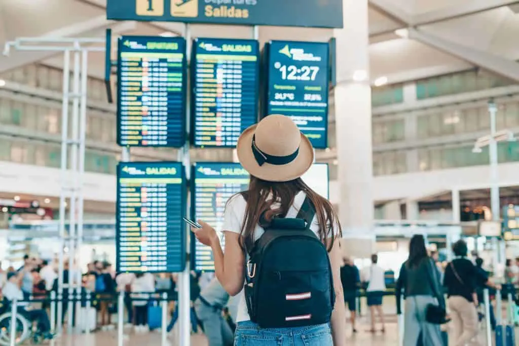 turista no aeroporto olha os painéis de voos