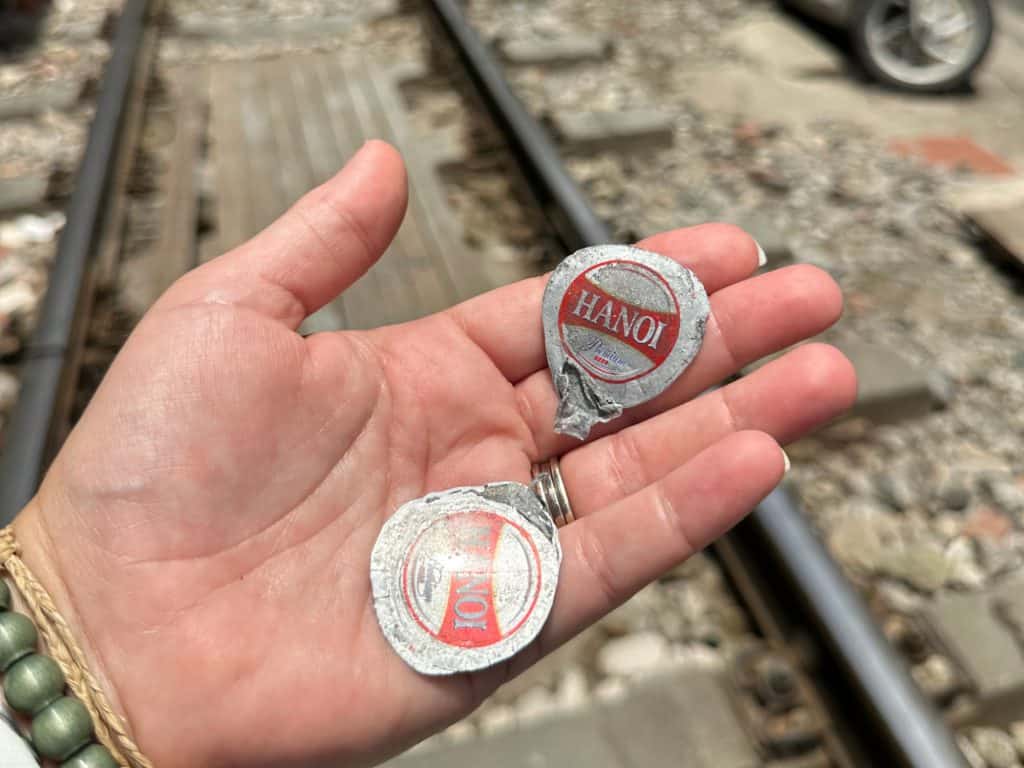 The palm of my hand holding two flattened beer caps