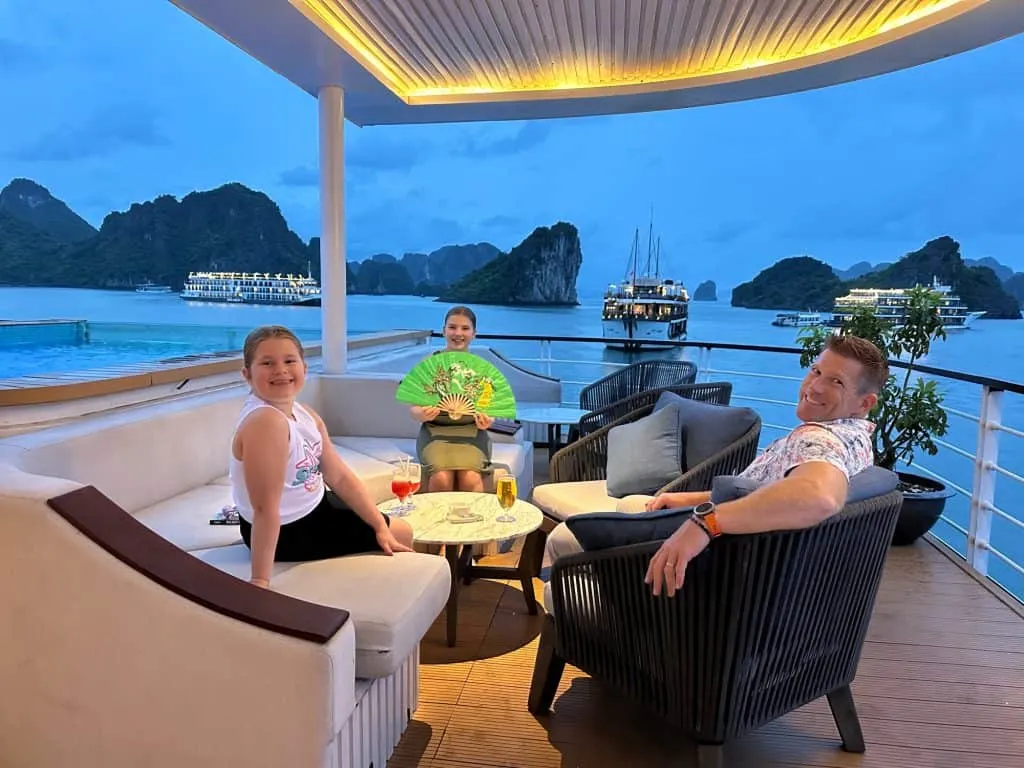 Mr Tin Box and daughters sat beside the pool on Mon Cheri 2 in the evening. The sky is going dark but you can see th bay behind them