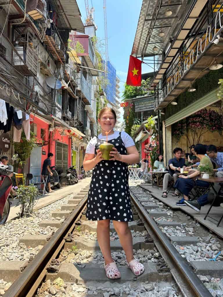 Our nine-year-old stood on the tracks on Hanoi's Train Street drinking from a coconut