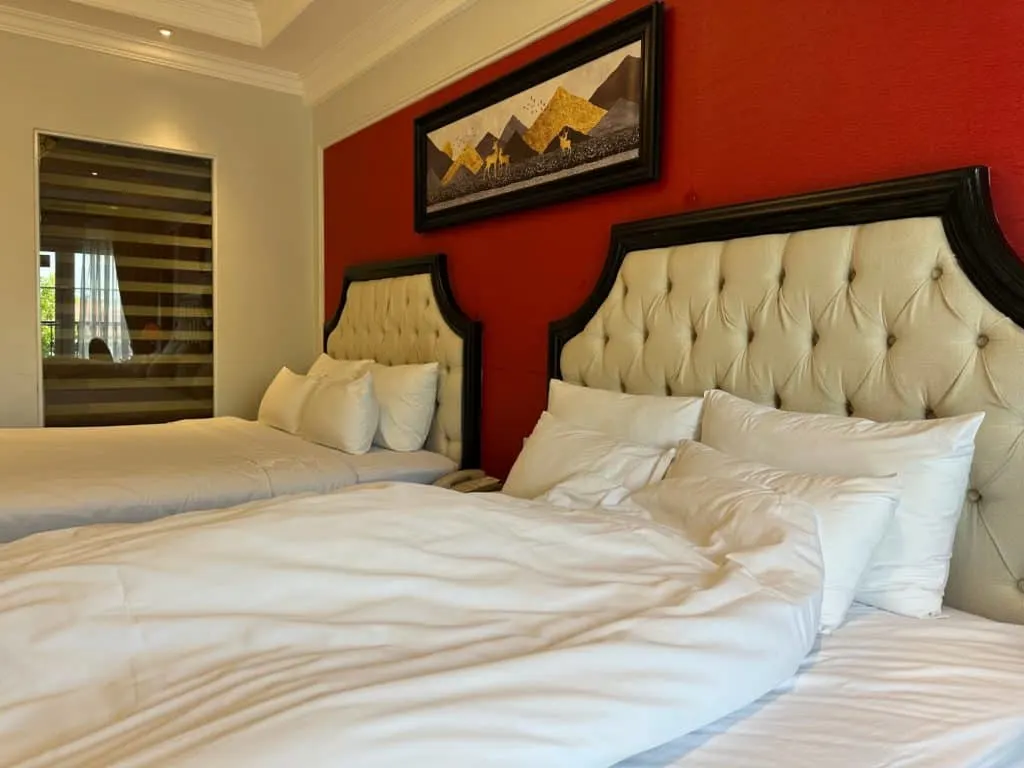 Two double beds with leather headboards and white linen