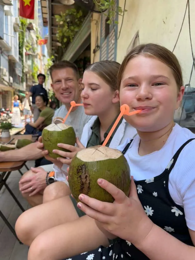 O Sr. Tin Box e nossas filhas desfrutando de uma bebida de coco ao lado dos trilhos do trem na famosa Train Street de Hanói