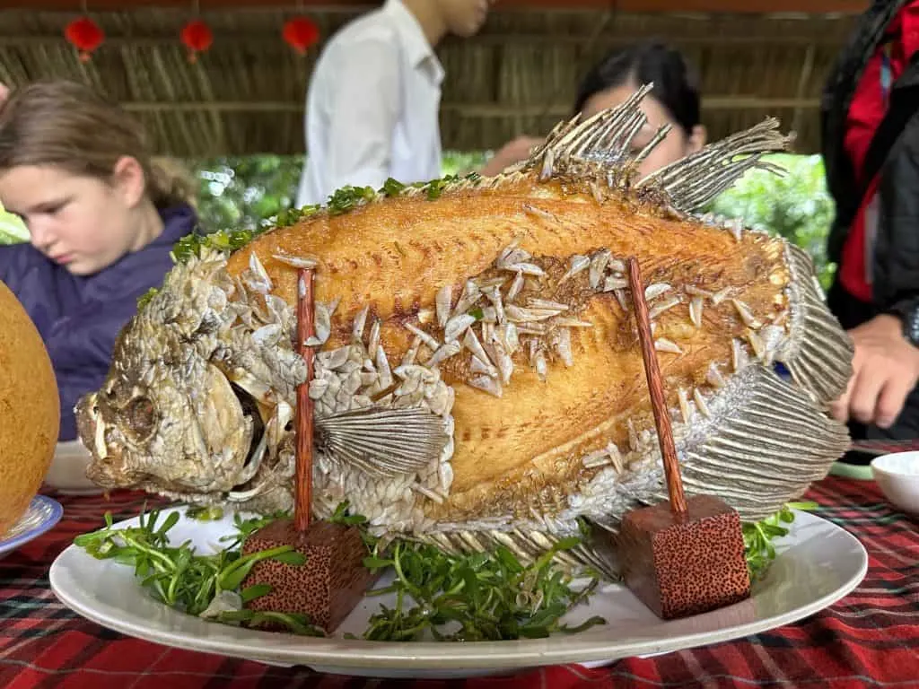 A cooked fish stood upright in a wooden holder