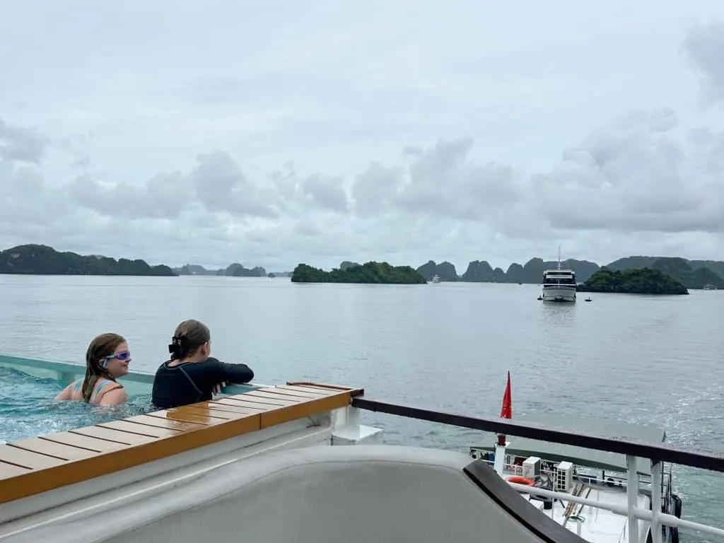 Our two daughters chatting at the end of the infinity pool. There's a view of Ha Long Bay and another cruise ship