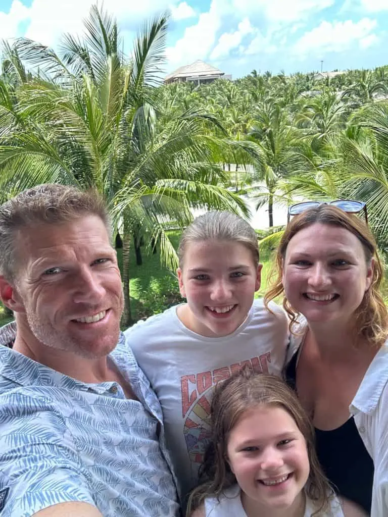 Our family smiling. There is a few of palm trees behind us