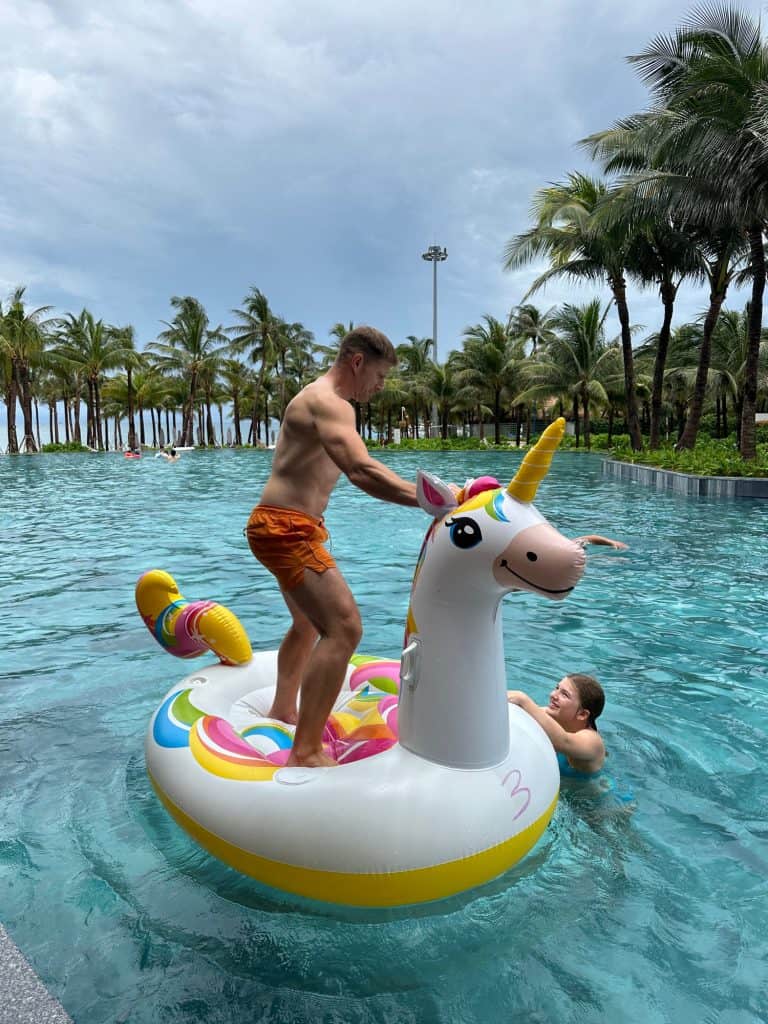 Mr Tin Box is stood on the back of a unicorn inflatable in the pool at New World Phu Quoc Resort