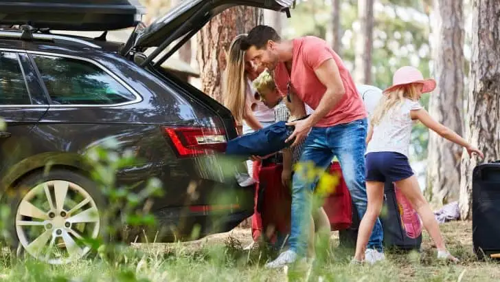 Family at the car loading from the trunk with luggage before traveling