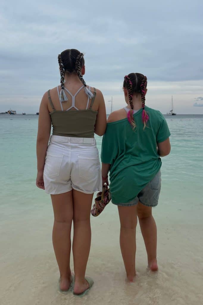 My daughters stood looking at the sea from Pattaya Beach. They have just had their hair braided and their braids hang down their backs