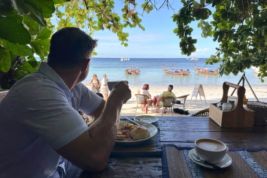 My husband drinking a coffee at Cafe Lipe in Koh Lipe and looking out over Pattaya Beach