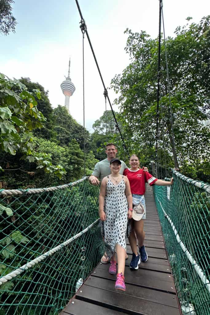 My family stood on the canopy walk in KL Urban Jungle with he KL Tower visible above the canopy