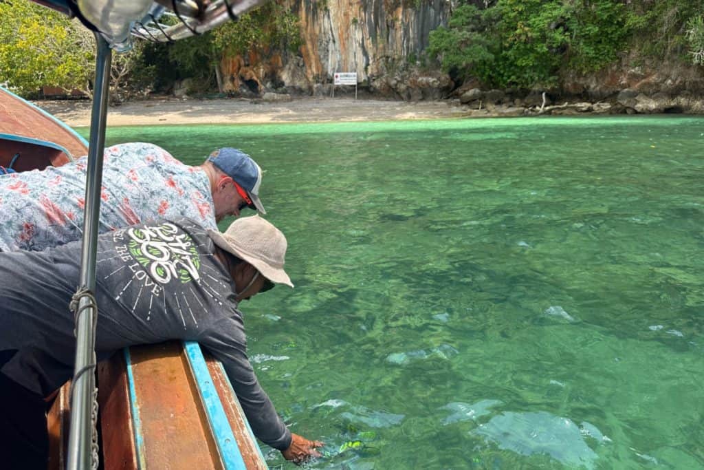 My husband and out guide, Rokin feeding pineapple chunks to tropical fish of a small island near Krabi