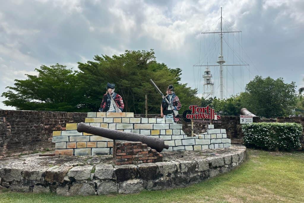 My daughters looking through cut outs in the faces of two wooden colonial soldiers at Cornwallis Fort in Penang