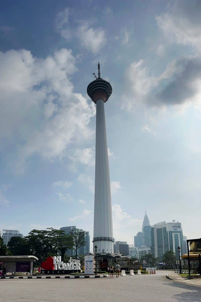 A view of Kuala Lumpur's iconic LK Tower from below with the rest of the city skyline looking small at the bottom