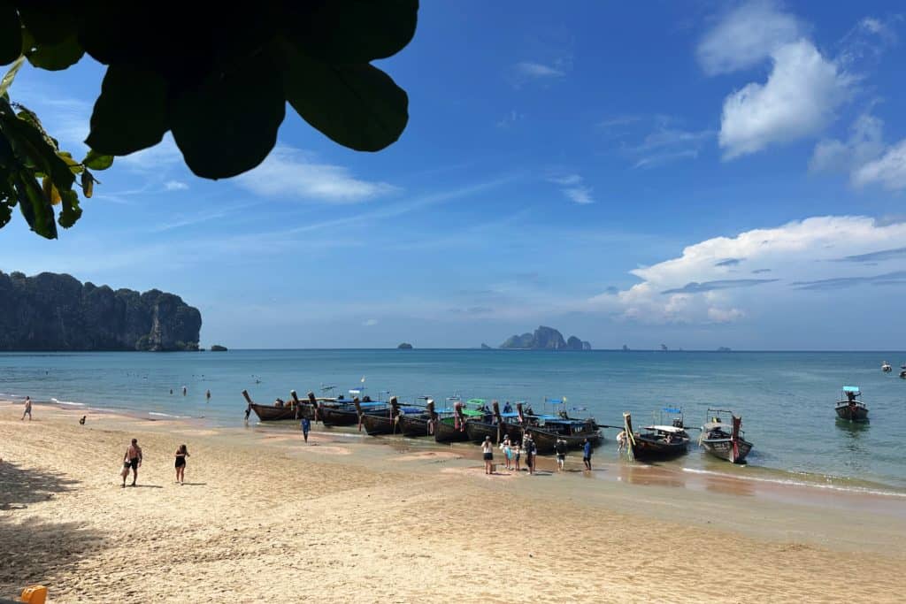 Longtail boats are pulled up on the beach at Ao Nang in Krabi waiting to take tourists to nearby Railey