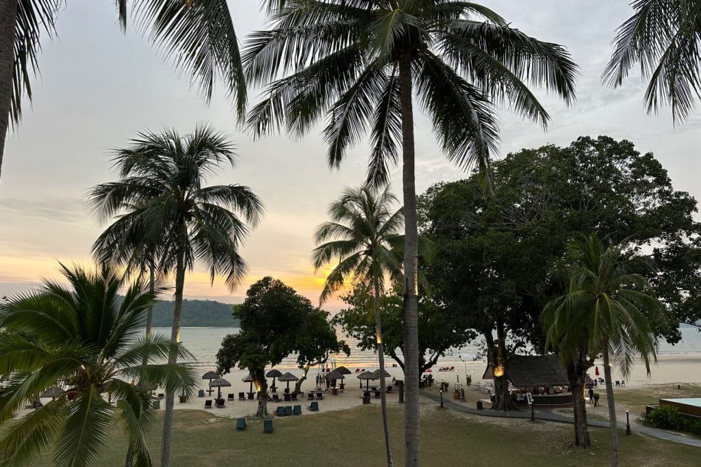 A view from our room at Holiday Villas Langkawi with the beach visible through palm trees of the beach through palm trees