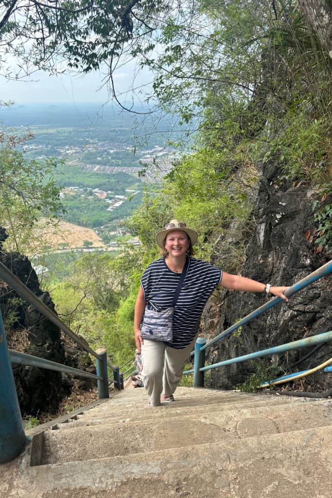 Me looking very sweaty on the steps up to the Tiger Cave. Behind me is a scenic view of fields in rural Krabi