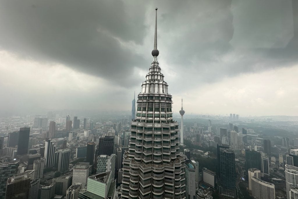 Kuala Lumpur Tower standing tall over the cityscape under stormy skies.