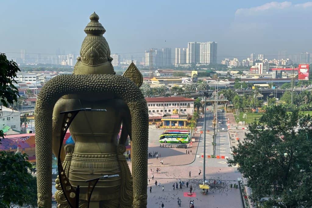 Batu Caves Temple statue overlooking a busy cityscape with modern buildings in the background. Kuala Lumpur, Malaysia