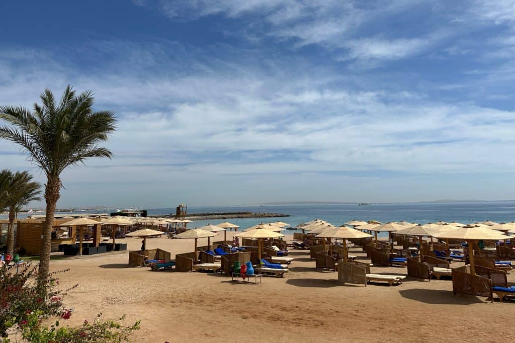 Tumbonas y sombrillas alineadas en la playa de arena frente al Mercure Hurghada con vistas al Mar Rojo