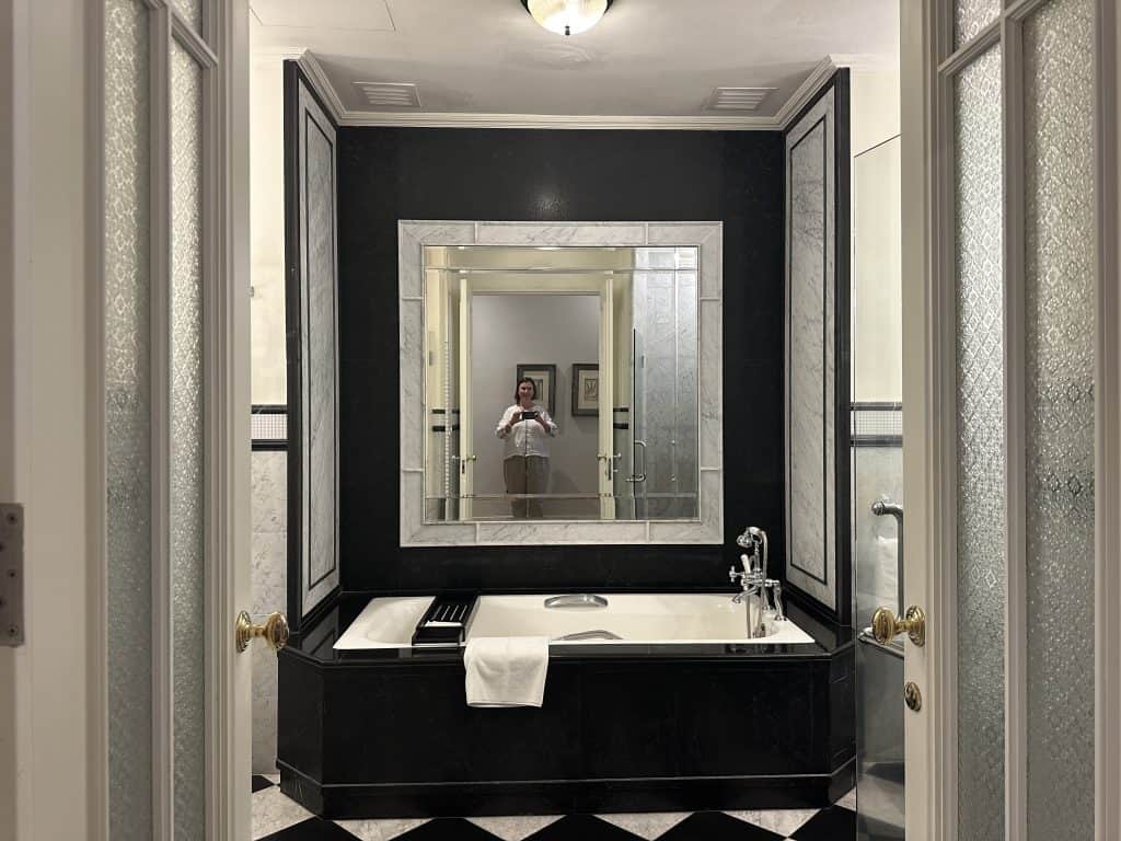 The bathroom of our heritage wing suite at the E&O. It is decked with dark wood and black and white tiled floors